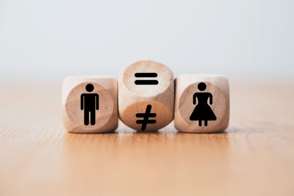 Wooden blocks show a man icon, an equals/not-equals pair in the center, and a woman icon—conveying gender equality and inequality.